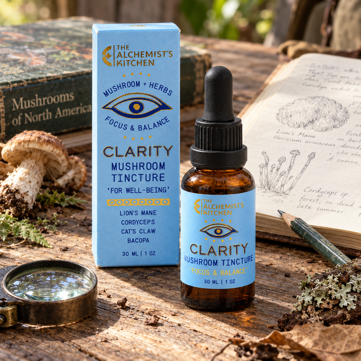 The Alchemist’s Kitchen Clarity Mushroom Tincture bottle and blue carton on a weathered field-study table with a mushroom guide, notebook, magnifying lens, pencil, mushrooms, and lichen.